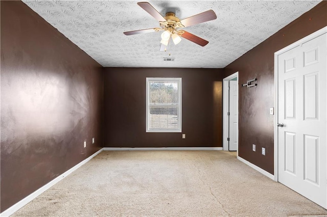 carpeted empty room featuring ceiling fan and a textured ceiling