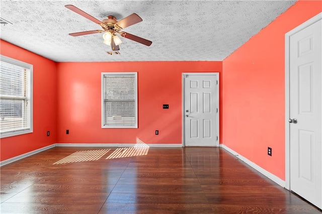 empty room with a textured ceiling, dark hardwood / wood-style floors, and ceiling fan