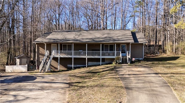 view of front facade with driveway, covered porch, stairway, and an outbuilding