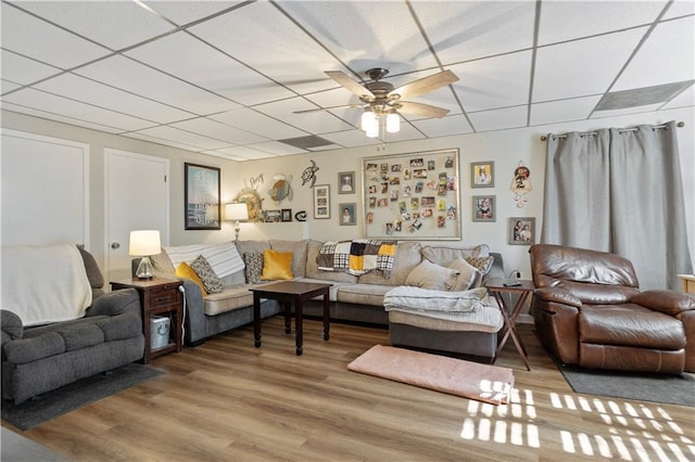 living room featuring a paneled ceiling, ceiling fan, and wood finished floors