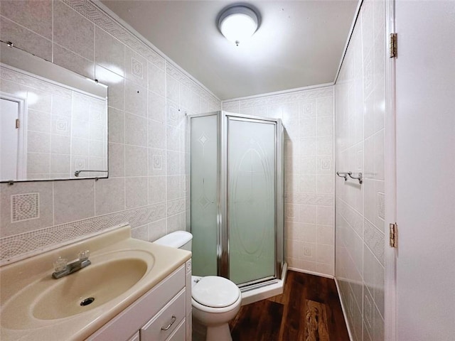 bathroom with toilet, a stall shower, wood finished floors, tile walls, and vanity