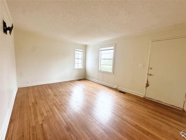 empty room with a textured ceiling, baseboards, and wood finished floors