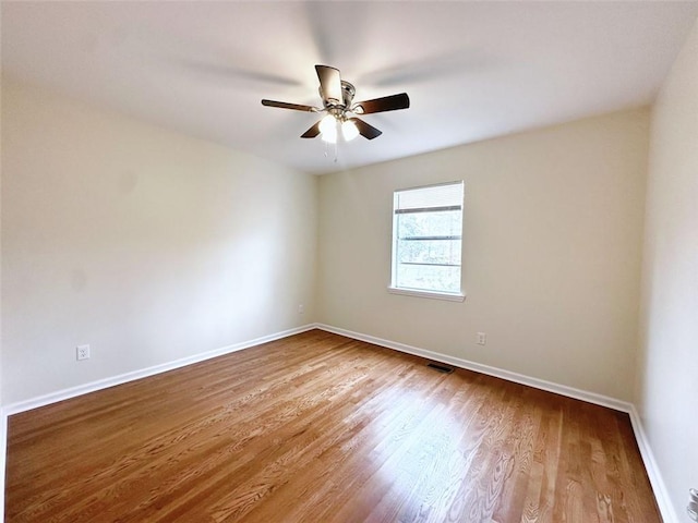 empty room with visible vents, baseboards, wood finished floors, and a ceiling fan