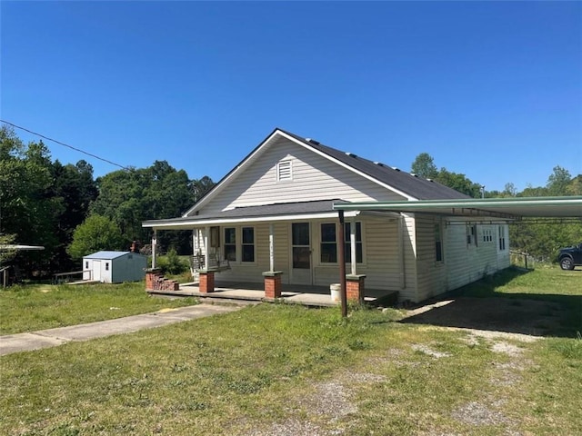 view of front of home featuring a porch, a carport, a shed, and a front yard