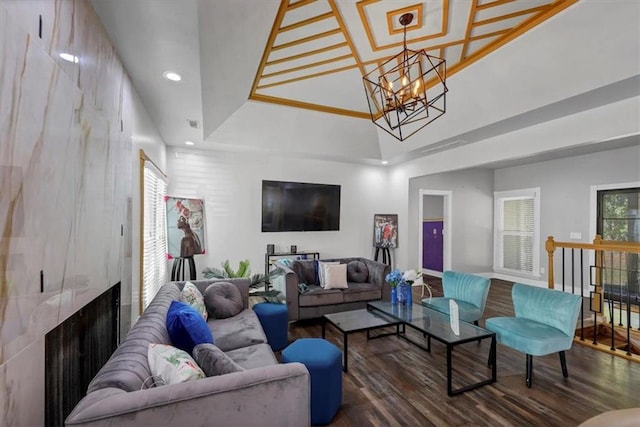 living room with a notable chandelier, dark hardwood / wood-style floors, and a large fireplace