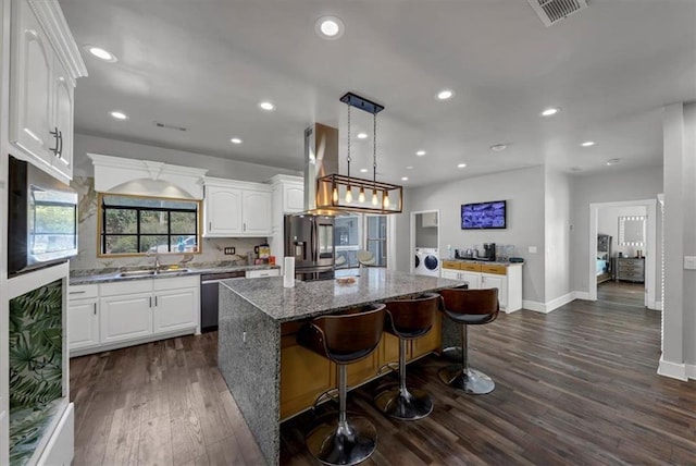 kitchen featuring sink, a kitchen island, independent washer and dryer, white cabinets, and dark hardwood / wood-style floors