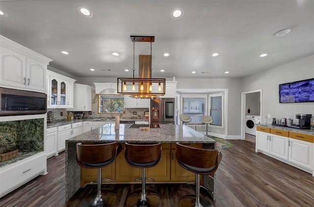 kitchen featuring appliances with stainless steel finishes, white cabinetry, decorative light fixtures, and dark hardwood / wood-style floors