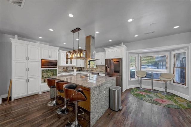 kitchen featuring appliances with stainless steel finishes, backsplash, a center island, white cabinetry, and light stone counters