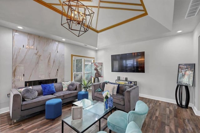 living room with a towering ceiling, an inviting chandelier, dark hardwood / wood-style floors, and a high end fireplace