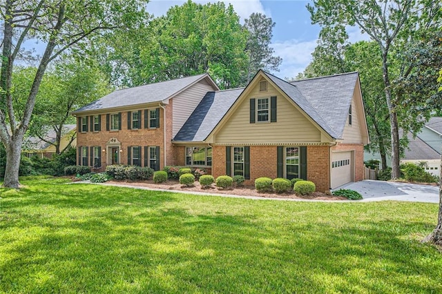 colonial house featuring a front yard, driveway, a shingled roof, and brick siding
