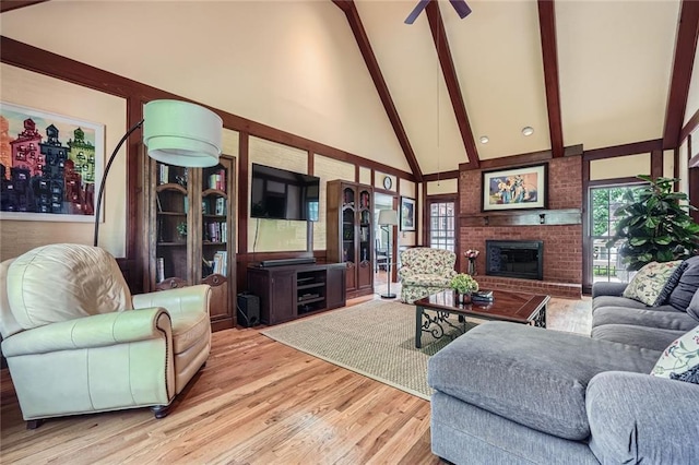 living area featuring beamed ceiling, plenty of natural light, a brick fireplace, wood finished floors, and high vaulted ceiling