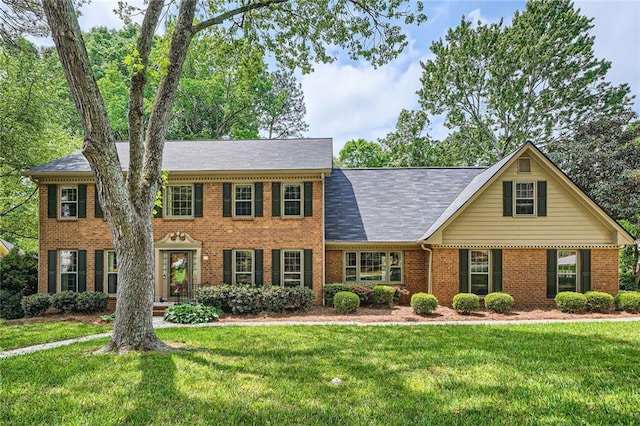 colonial-style house featuring brick siding and a front yard