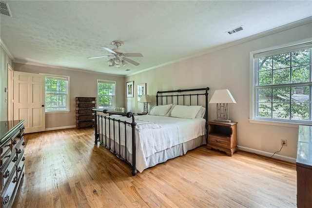 bedroom with crown molding, visible vents, baseboards, and light wood-type flooring