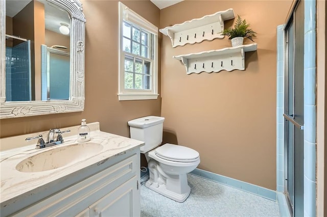 bathroom with vanity, toilet, a stall shower, and baseboards