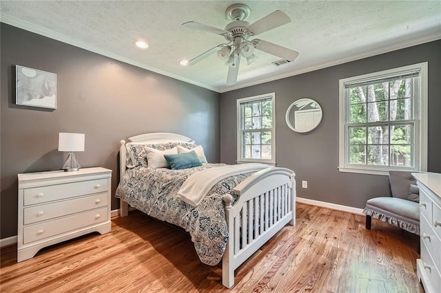 bedroom with light wood finished floors, visible vents, ornamental molding, and baseboards
