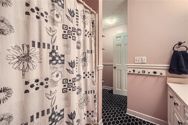 bathroom featuring a textured ceiling, vanity, a shower with shower curtain, and baseboards