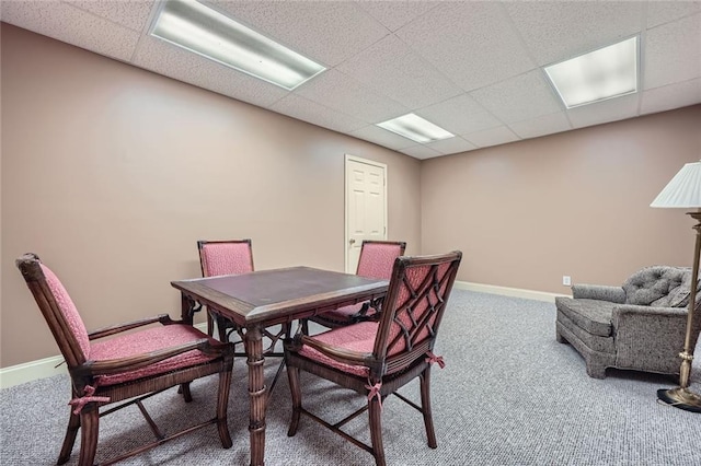 carpeted dining area featuring a paneled ceiling and baseboards