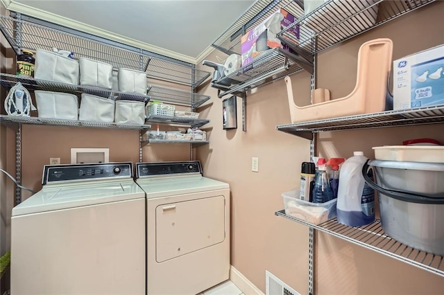 clothes washing area featuring washing machine and dryer, visible vents, laundry area, and baseboards