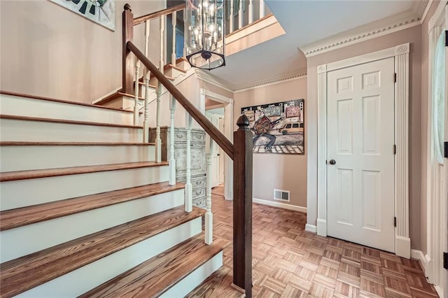 stairs featuring baseboards, visible vents, ornamental molding, and an inviting chandelier
