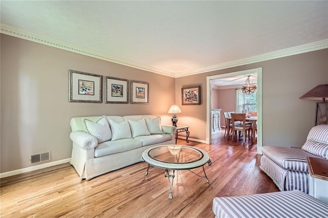 living room featuring ornamental molding, visible vents, wood finished floors, and baseboards