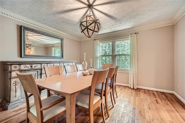 dining space featuring baseboards, light wood-type flooring, ornamental molding, and a textured ceiling