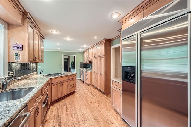 kitchen with recessed lighting, a sink, stainless steel appliances, light wood-style flooring, and ornamental molding