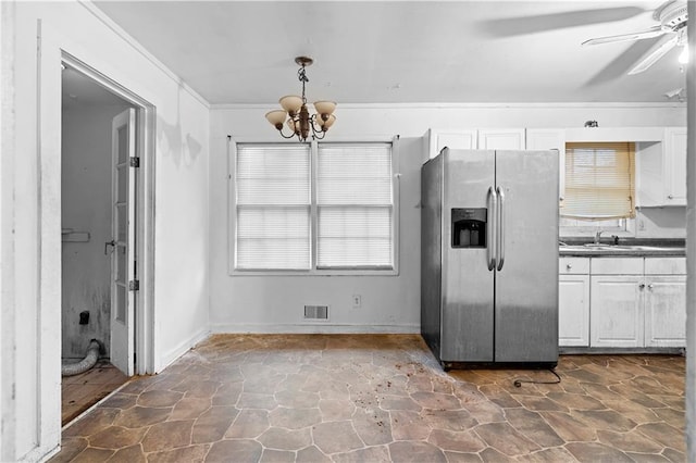 kitchen with white cabinets, sink, stainless steel fridge, and decorative light fixtures