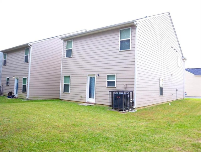 back of house featuring central air condition unit and a lawn