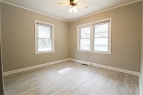 empty room featuring light wood finished floors, baseboards, ornamental molding, and a ceiling fan