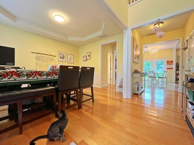 dining area featuring a chandelier, light wood-type flooring, and wainscoting