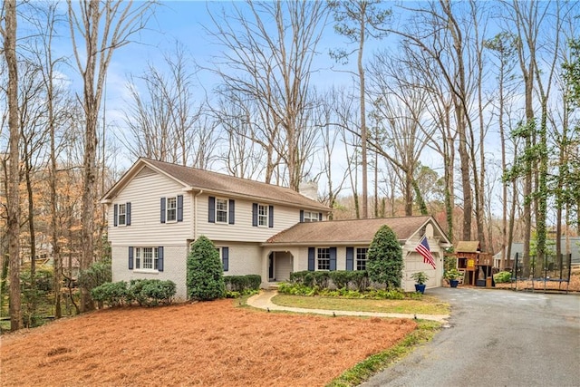view of front of property featuring driveway, a chimney, and brick siding