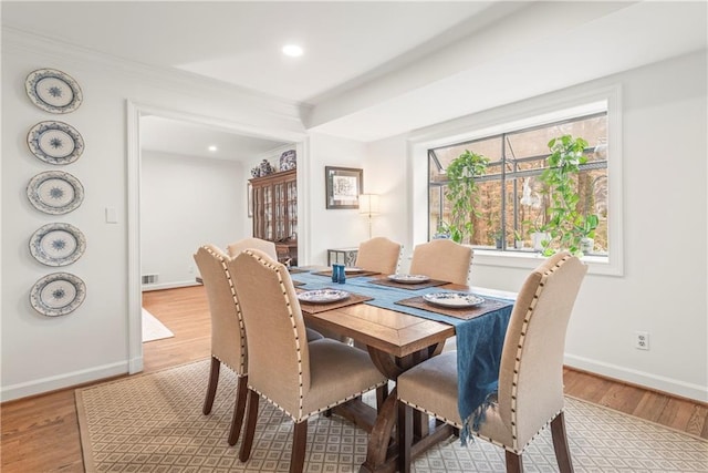 dining area with baseboards, light wood-type flooring, and visible vents