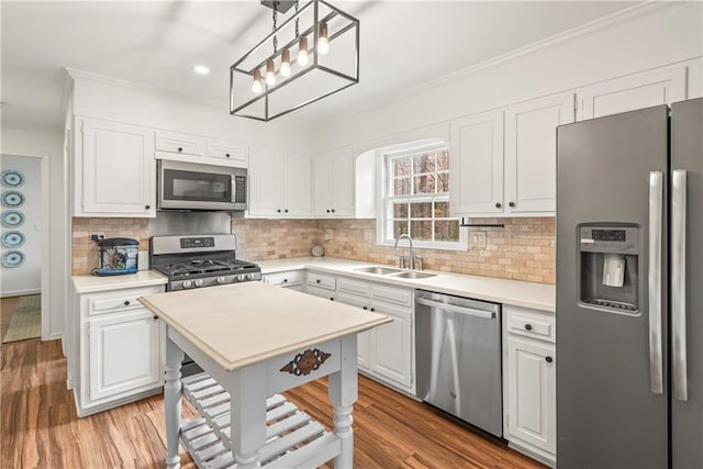 kitchen with light countertops, a sink, wood finished floors, stainless steel appliances, and white cabinets