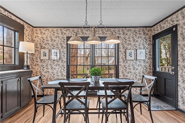 dining space with wallpapered walls, crown molding, and light wood-style floors