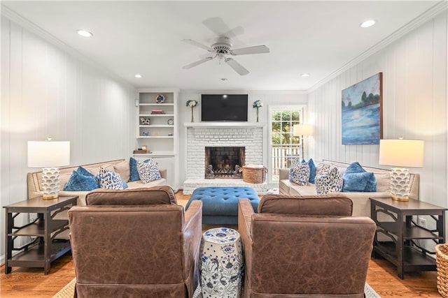 living area featuring built in features, ceiling fan, wood finished floors, and crown molding