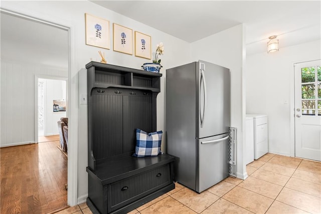 kitchen with freestanding refrigerator, washing machine and clothes dryer, light tile patterned floors, and baseboards