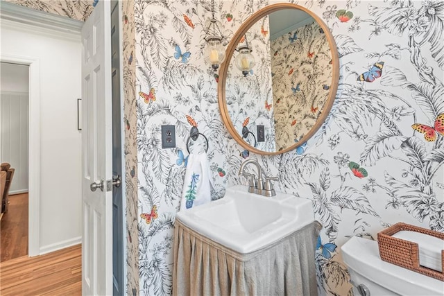 bathroom with wallpapered walls, toilet, baseboards, and wood finished floors