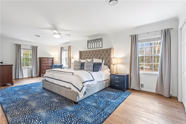 bedroom featuring crown molding, baseboards, light wood finished floors, and ceiling fan