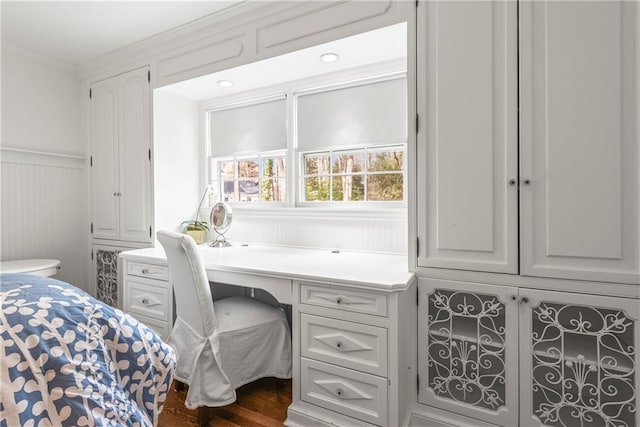 bedroom featuring a wainscoted wall, dark wood-style floors, a decorative wall, and ornamental molding