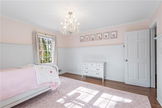 unfurnished bedroom with a wainscoted wall, ornamental molding, a chandelier, and wood finished floors
