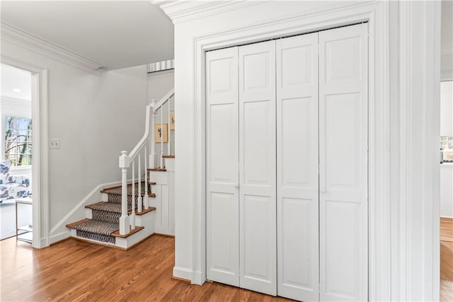 stairway featuring baseboards, wood finished floors, and ornamental molding