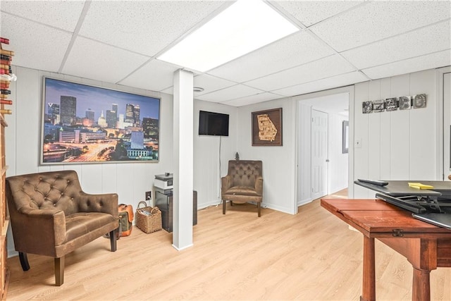 living area with light wood finished floors and a drop ceiling