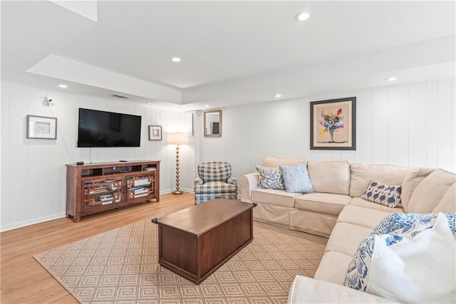 living room with recessed lighting, a tray ceiling, baseboards, and wood finished floors