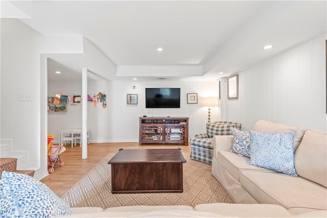 living area with baseboards, a tray ceiling, wood finished floors, and recessed lighting