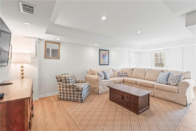 living area featuring recessed lighting, a tray ceiling, light wood-style floors, and visible vents