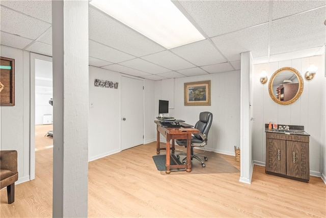 home office featuring baseboards, a paneled ceiling, and light wood-style floors