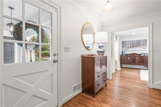 entryway featuring light wood-style flooring, ornamental molding, baseboards, and visible vents
