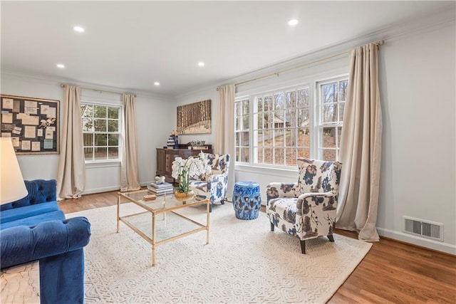 living room featuring ornamental molding, visible vents, recessed lighting, and wood finished floors