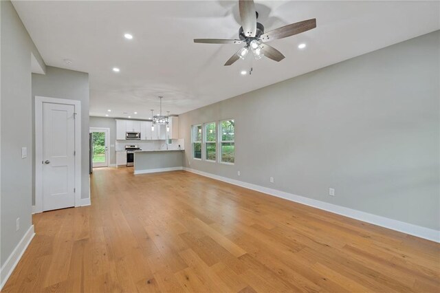 1857 Derrill Dr, Decatur, GA 30032 - unfurnished living room featuring baseboards, recessed lighting, light wood-style floors, and ceiling fan with notable chandelier