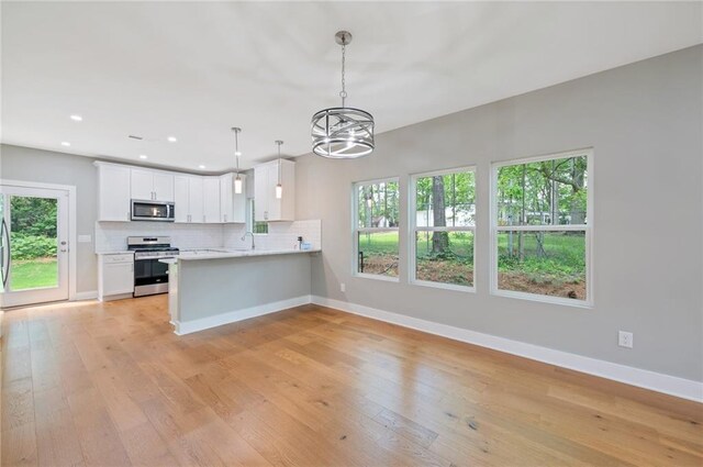1857 Derrill Dr, Decatur, GA 30032 - kitchen featuring a notable chandelier, light countertops, tasteful backsplash, light wood-type flooring, and stainless steel appliances